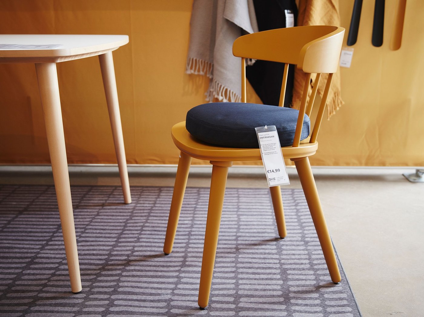 A Yellow OMTÄNKSAM chair with seat cushion close to a dining table.
