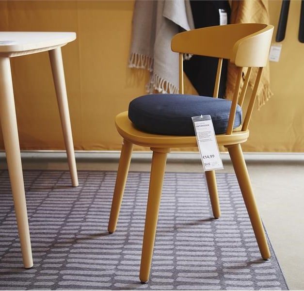 A Yellow OMTÄNKSAM chair with seat cushion close to a dining table.