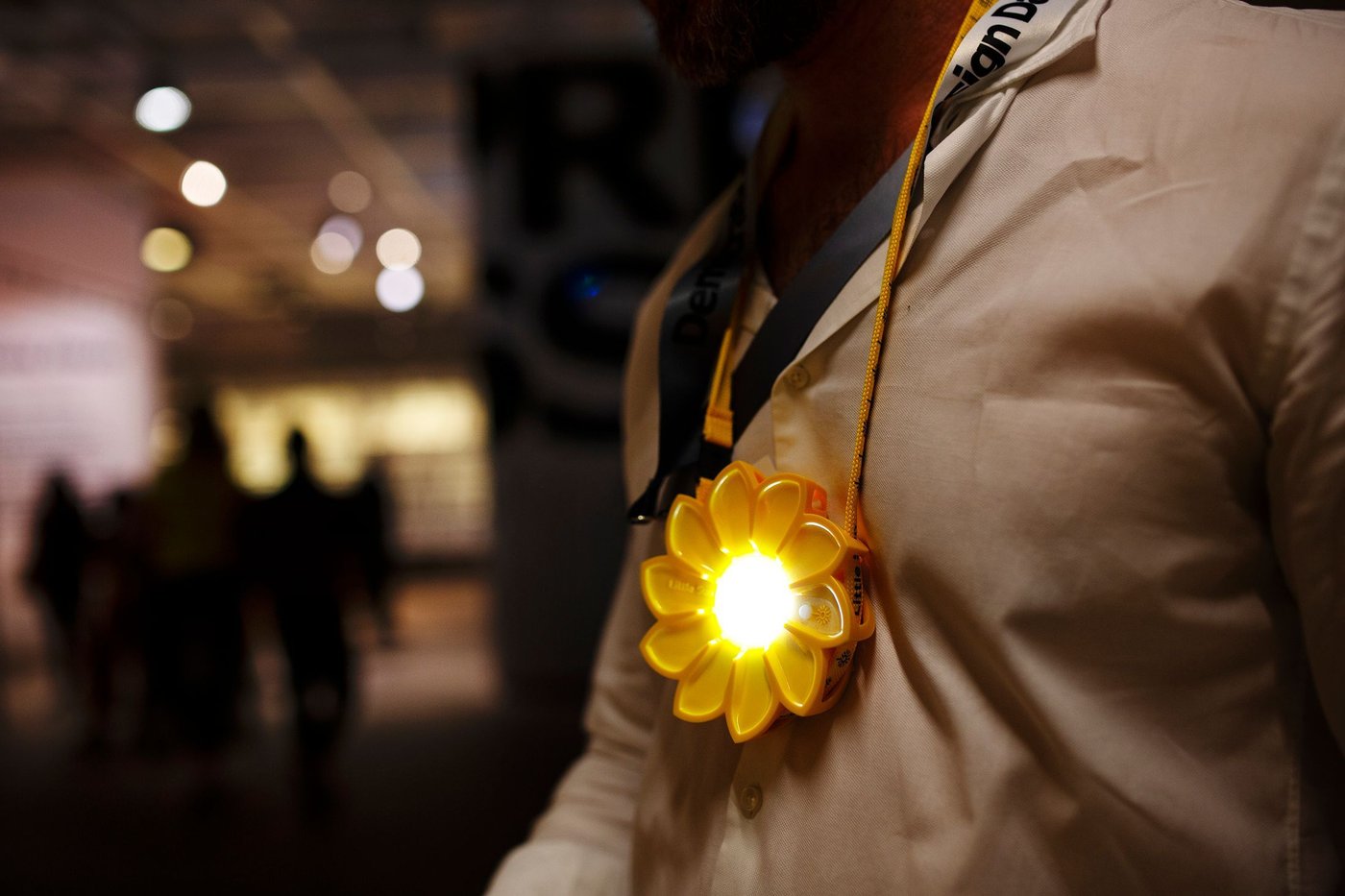 A person wearing a small sun-shaped lamp around their neck on a yellow cord.