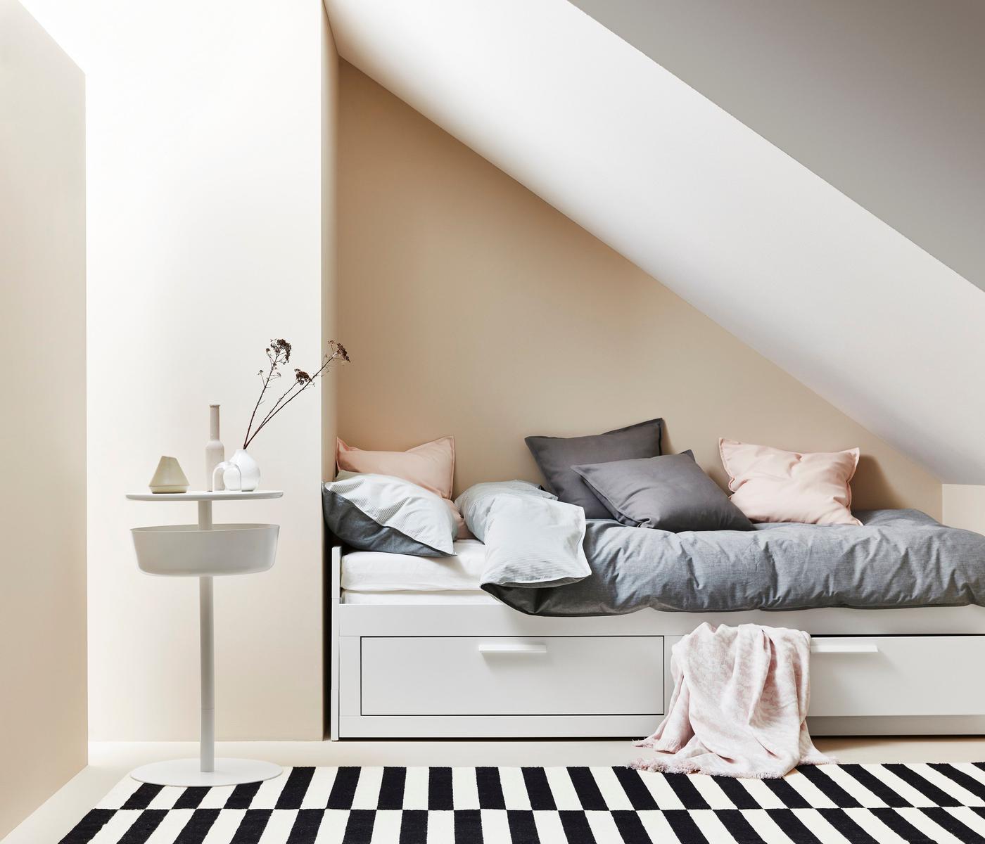 Bed with storage wedged perfectly into a triangular wall niche below a sloped ceiling.