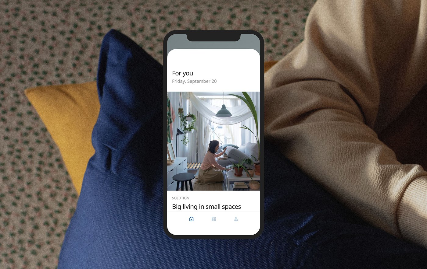 Visual of cushions with a person's arm in long sleeves overlaid with a smartphone screen showing small-space living content.