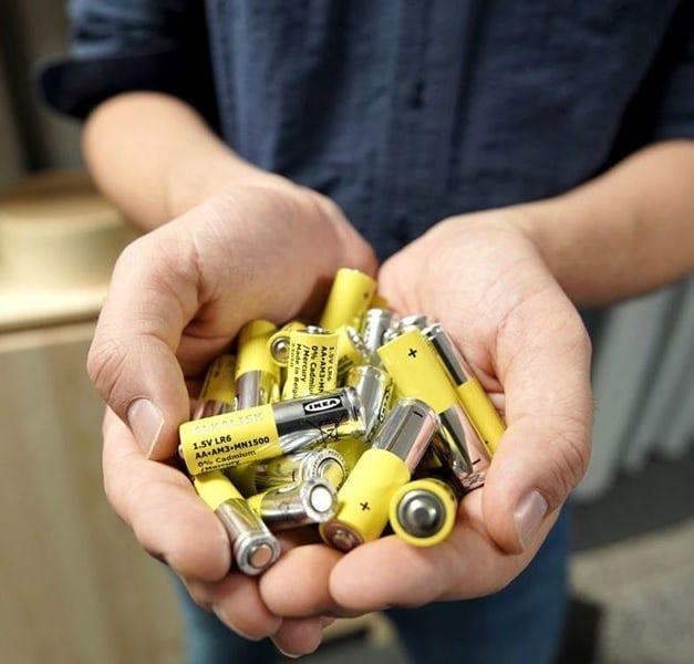 A pair of hands holding silver and yellow batteries.