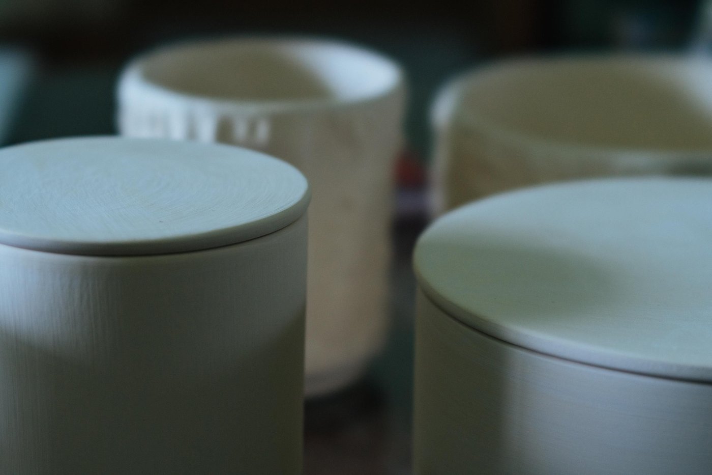 A collection of ceramic candle holders with candles in different sizes.