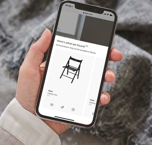 A person holds a smartphone. The screen shows a black chair on a white background.