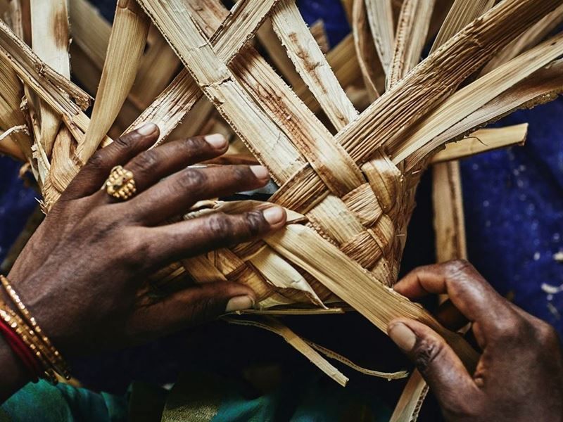 Hands weaving natural plant fronds.