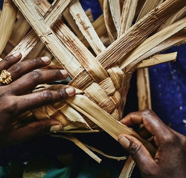 Hands weaving natural plant fronds.