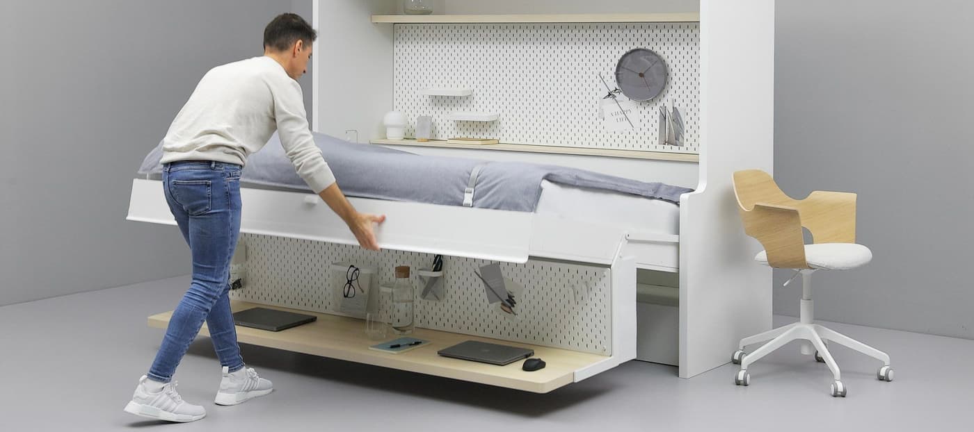 A man in a white shirt is folding a bed together.