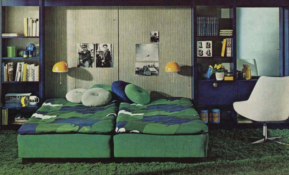 An image from the 1971 IKEA catalogue of a green bedroom with two beds placed together. Behind the beds is a large unit filled with shelves and books.