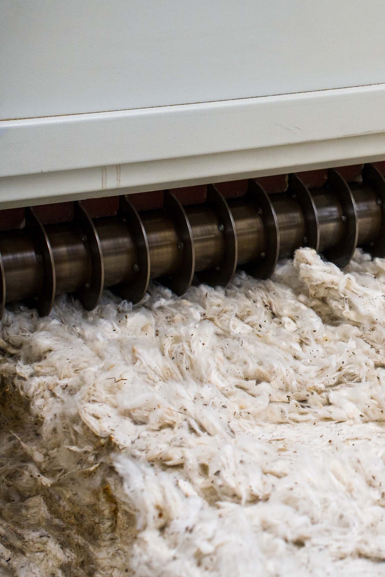 A factory machine cleans and combs white cotton lint.