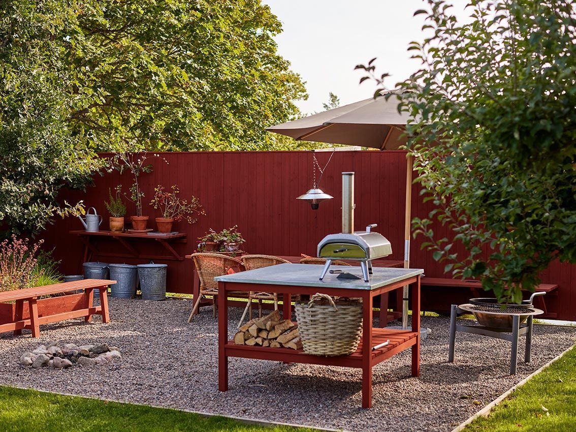 A gravelled outdoor kitchen and seating area with pizza oven.