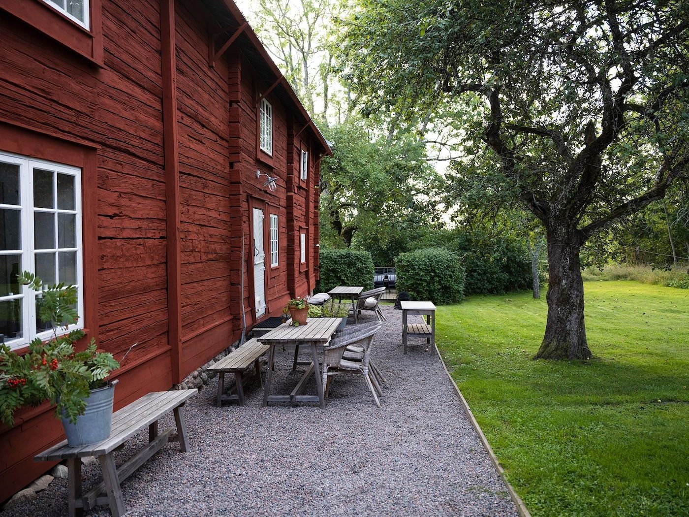A gravelled seating area outside a red Swedish farmhouse.