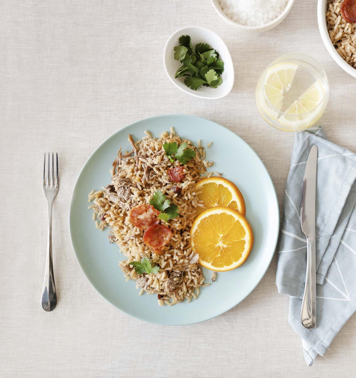A plate of rice with duck sits on a whitewashed wood table.