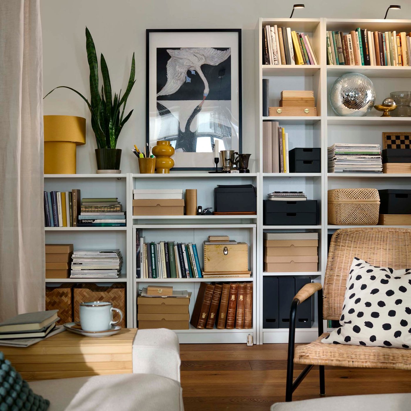 A well-organised living room with white BILLY bookcases filled with books, decorative items, and storage baskets.
