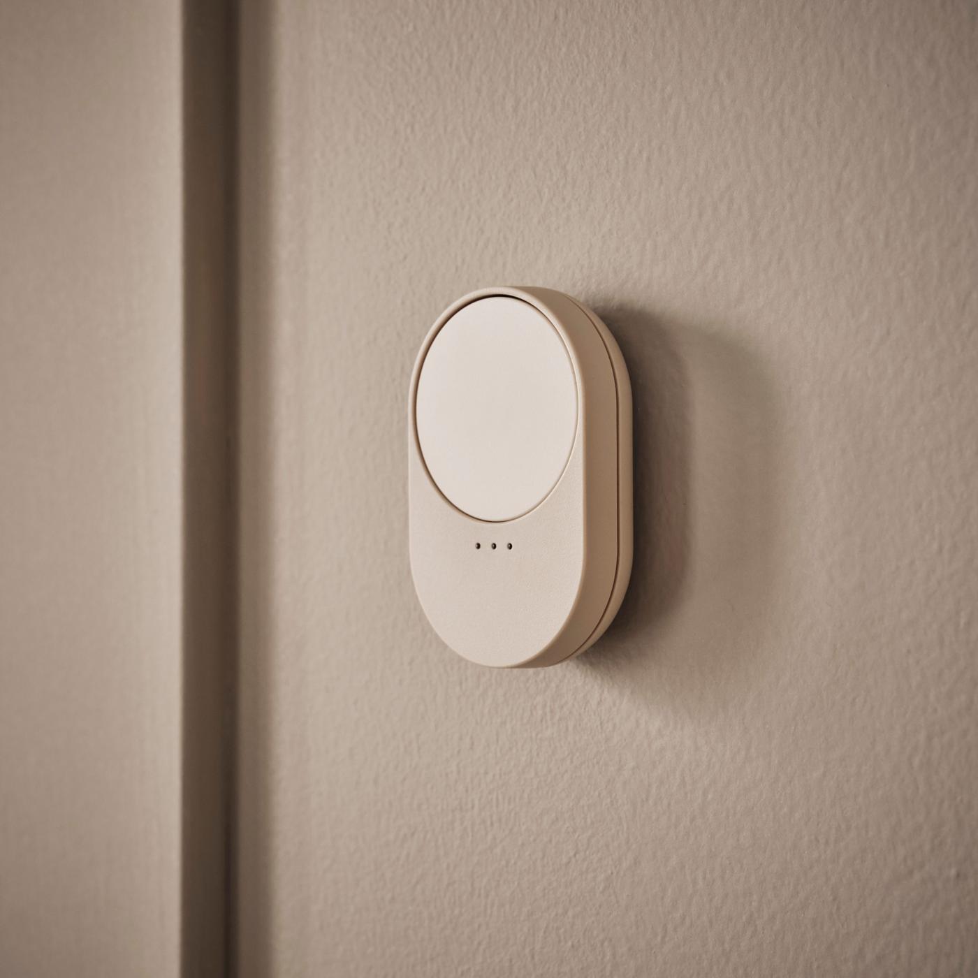 A beige remote with scroll wheel mounted on a brown-beige wall.
