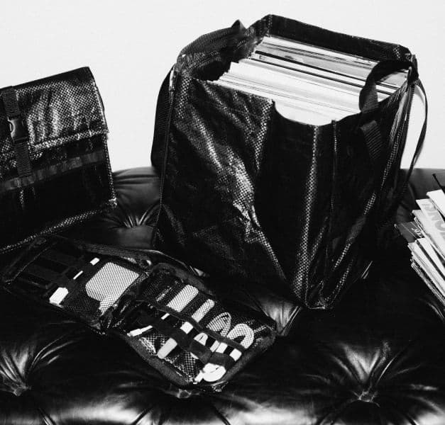 A black and white photo of black bags filled with cables and vinyl records.