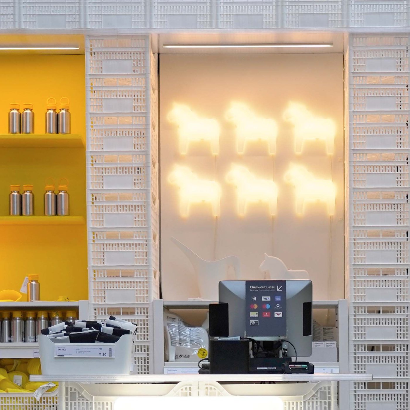 An IKEA pop-up shop with white crates as product shelves and illuminated horse-shaped lamps.