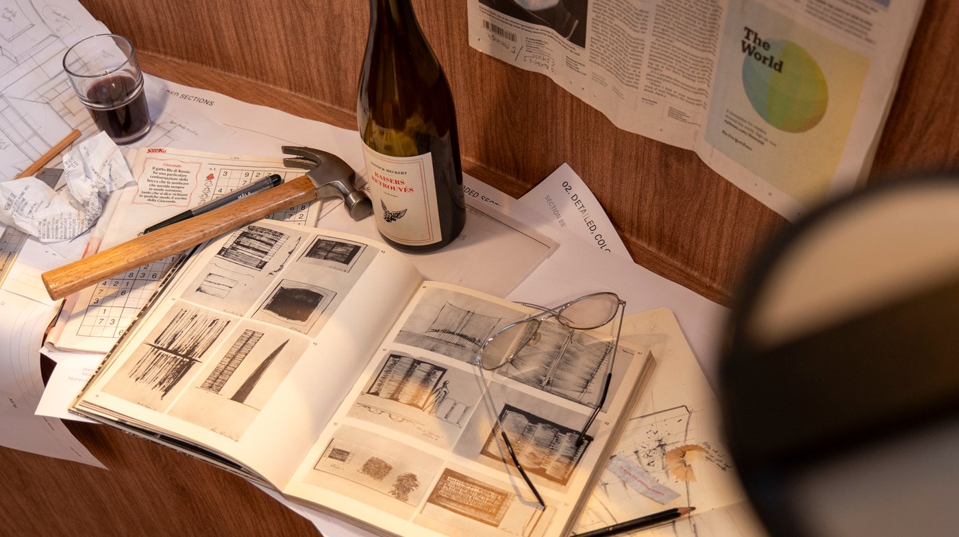 An aerial view of an open book, surrounded by papers, diagrams and a hammer.