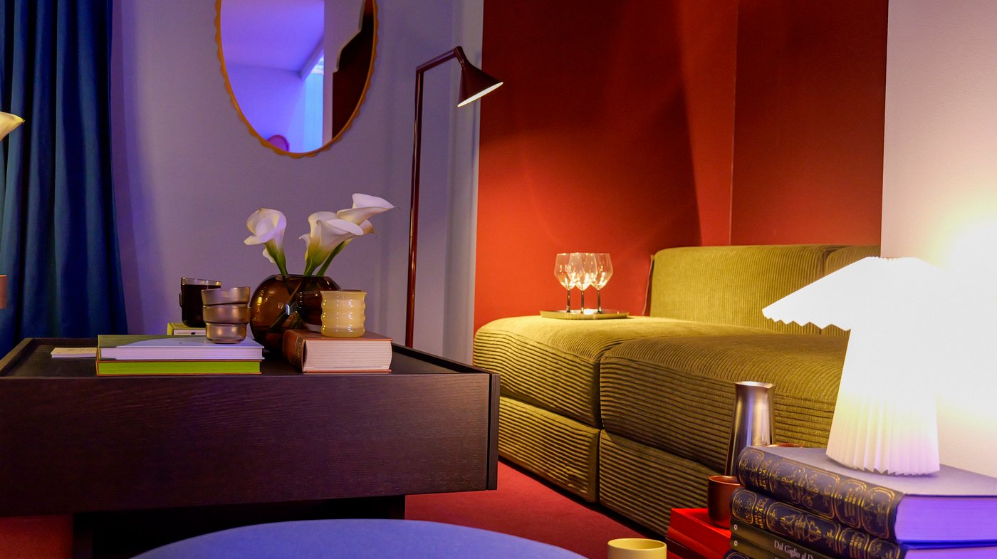 A colourful living room with a green sofa, dark wood coffee table and an illuminated lamp.