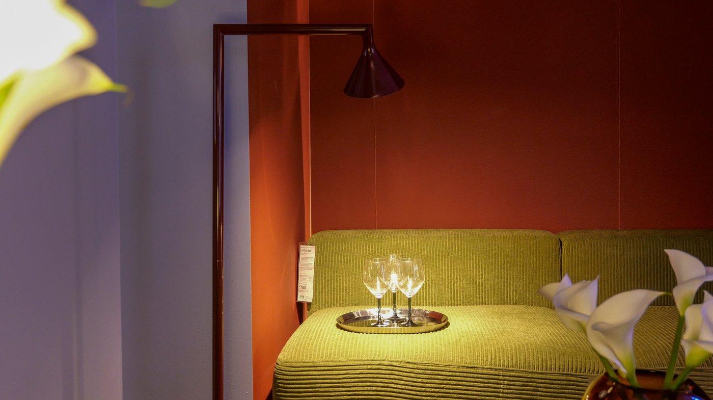 A lilac and red-brown room with a green sofa illuminated.