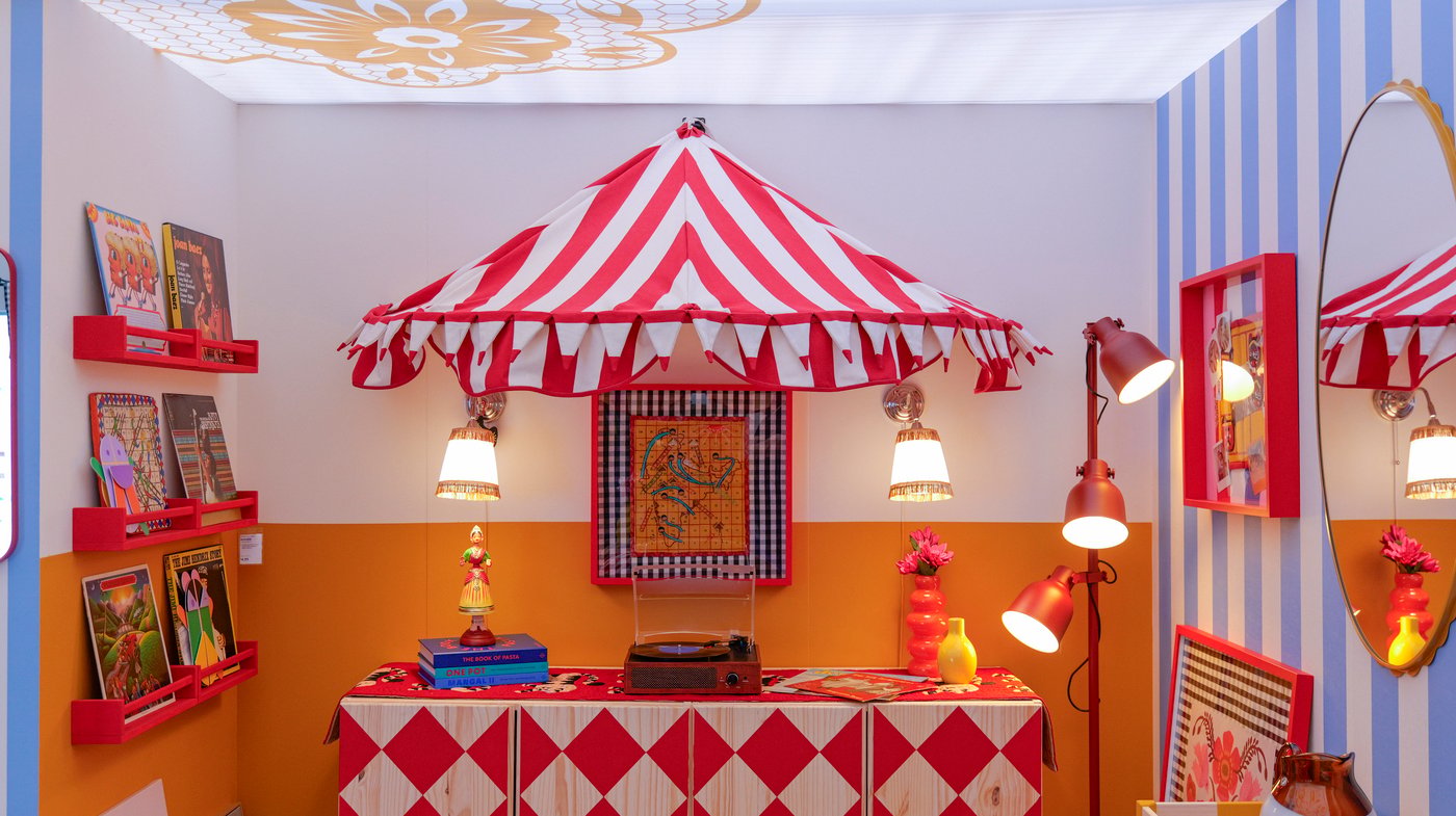 An alter-like table with a red striped awning above and two lamps in a graphic, colourful room.