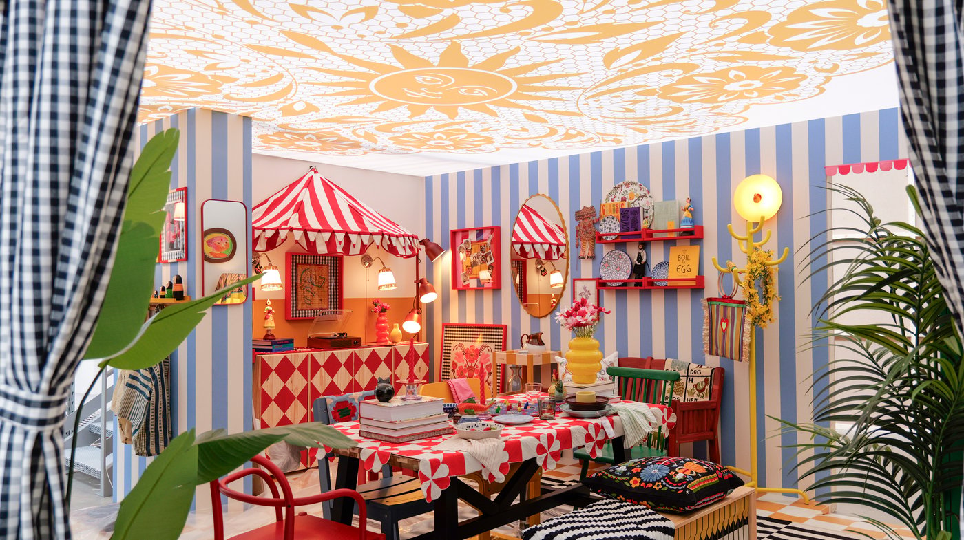 A decorative dining room with blue stripe wallpaper and red and blue patterned textiles and lots of decorations.