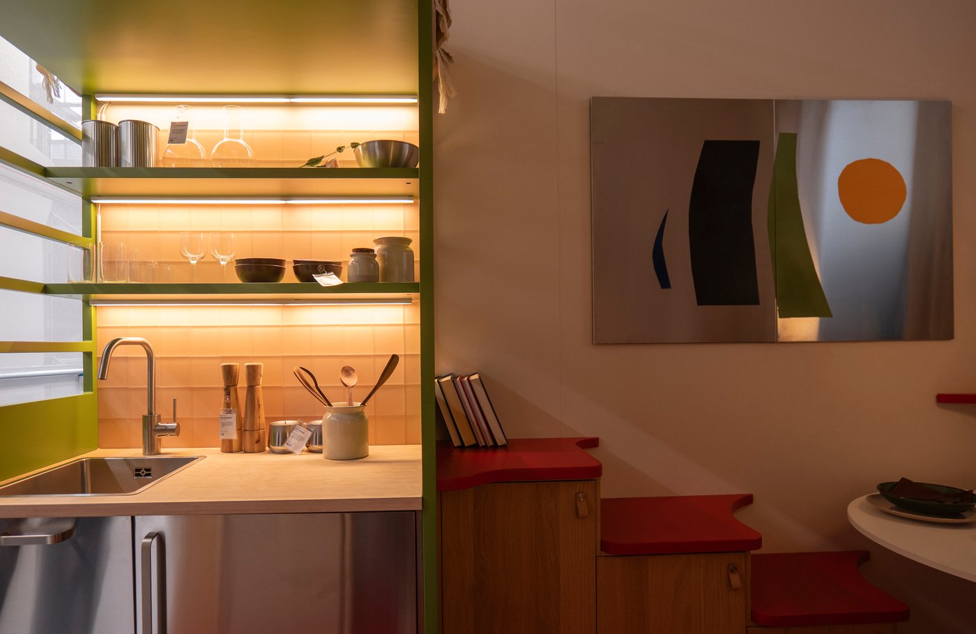 A kitchen-dining area with illuminated shelves above the sink.