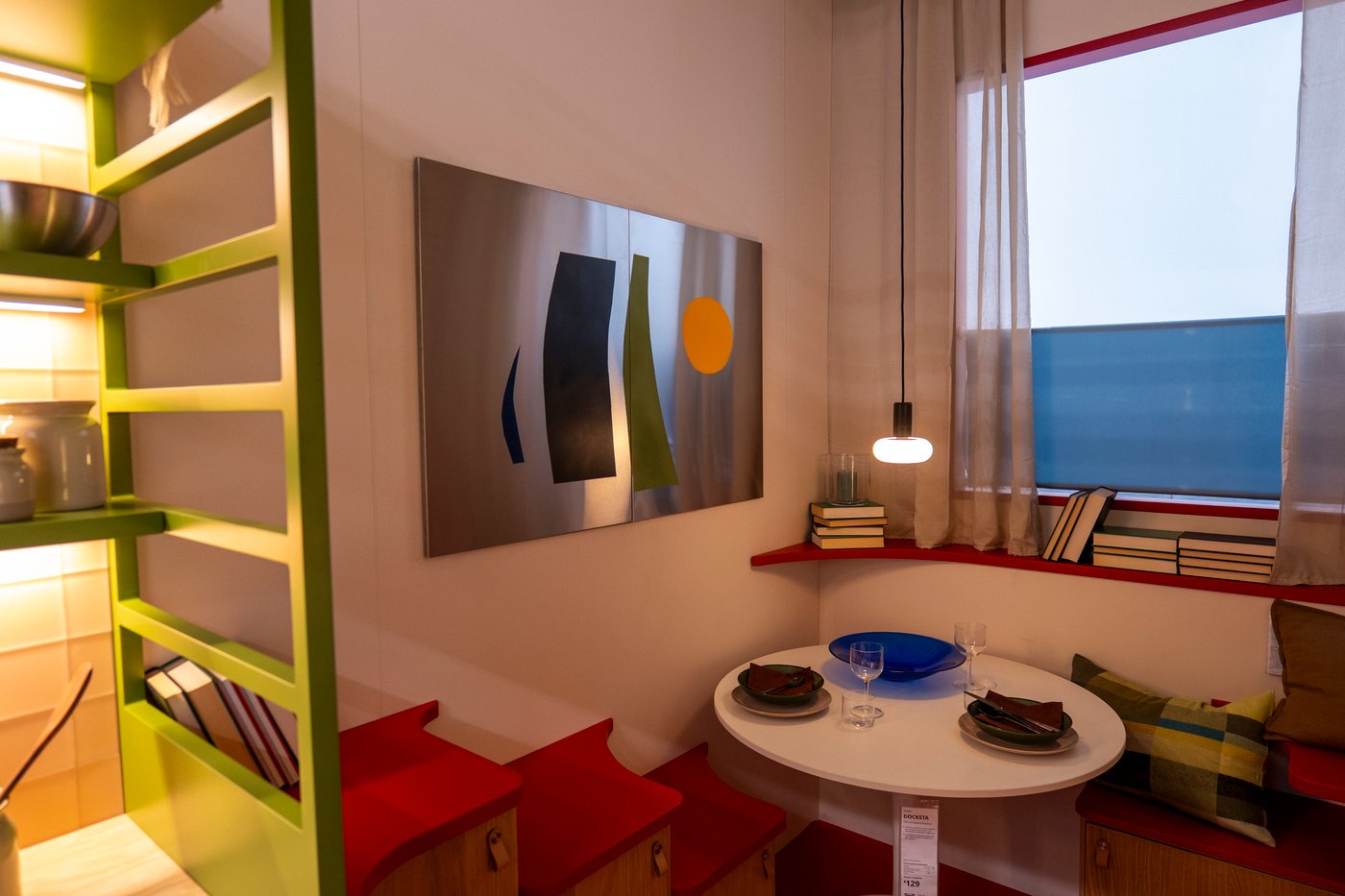 The corner of a studio room setting with a white dining room table below a window.