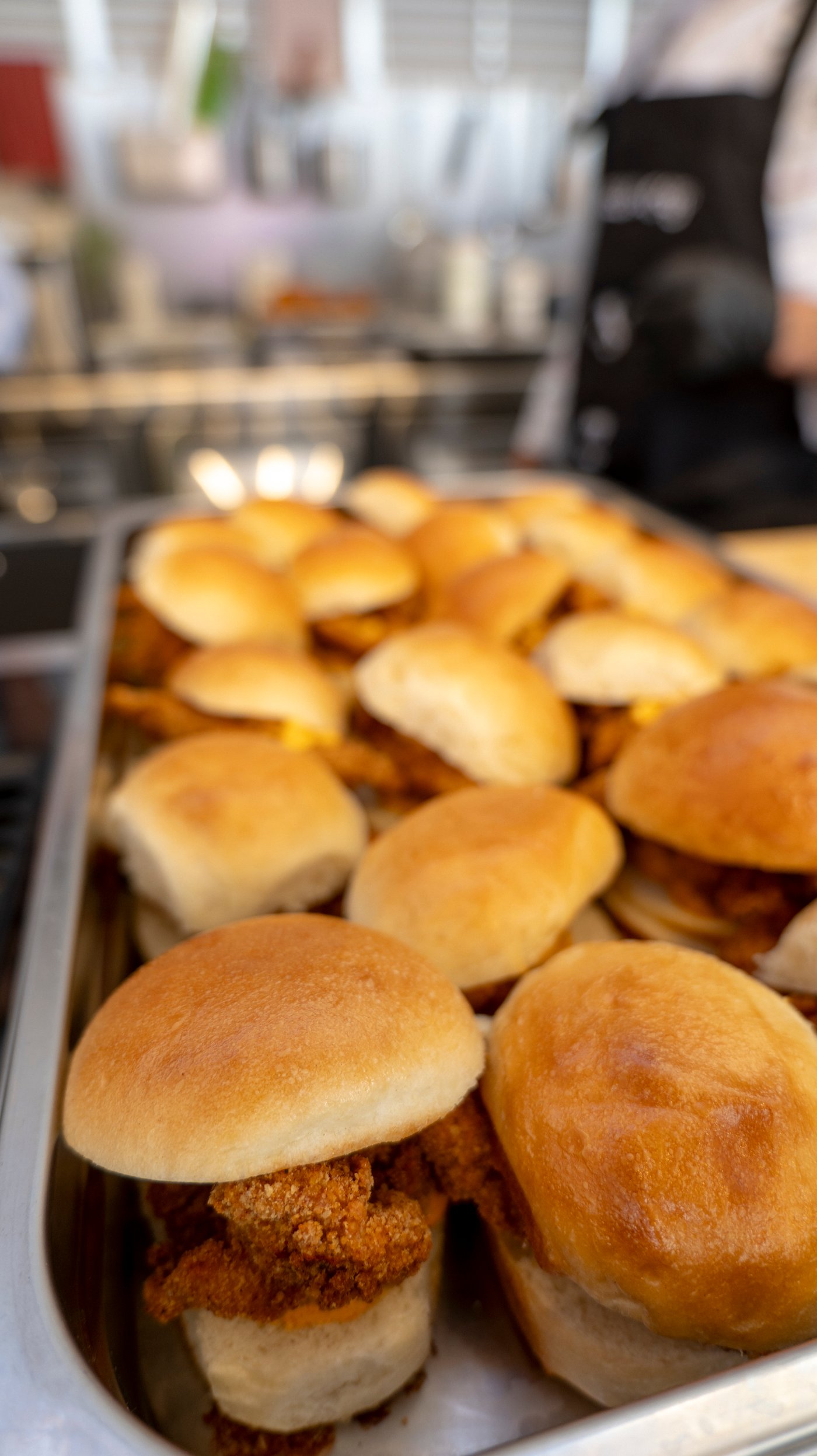 A close-up of a metal baking dish filled with chicken burgers.