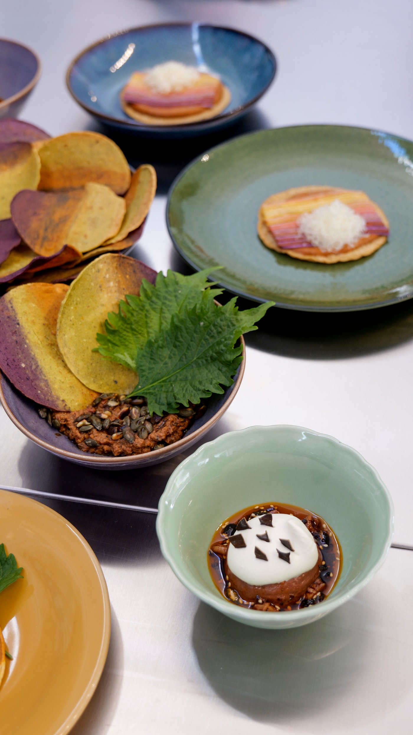 A collection of colourful plates with food on a metal surface.