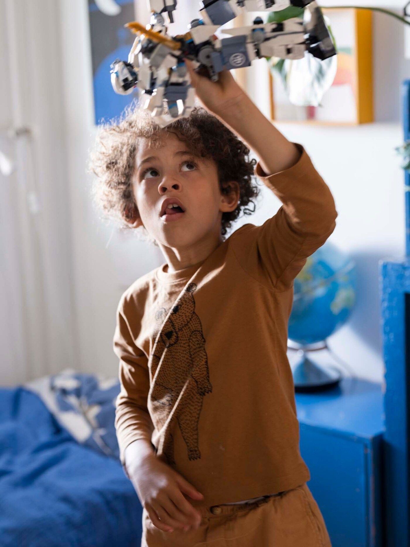 Victor plays with a toy in his blue bedroom