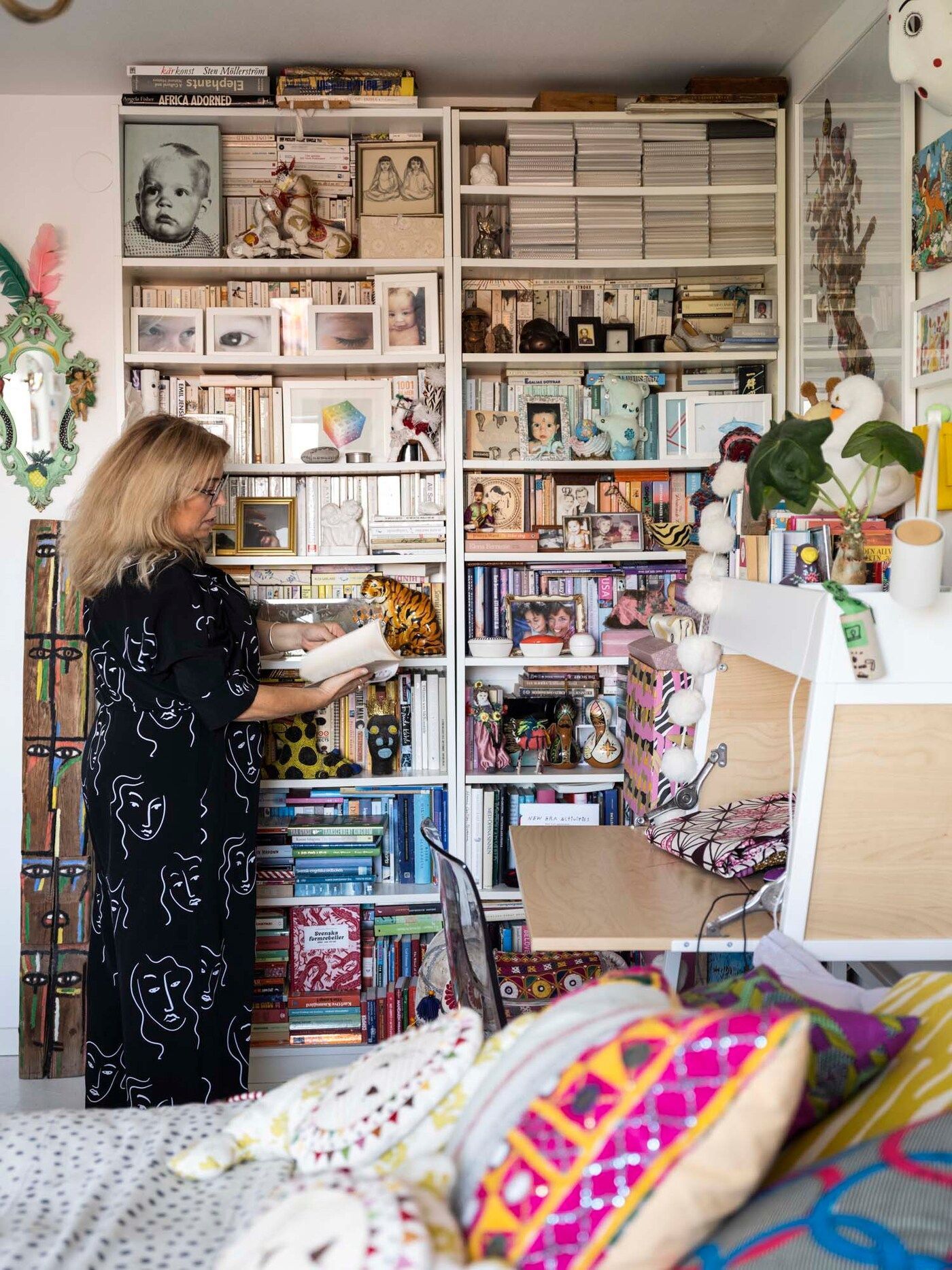 Cecilia stands in front of the bookshelf in her bedroom. She is reading