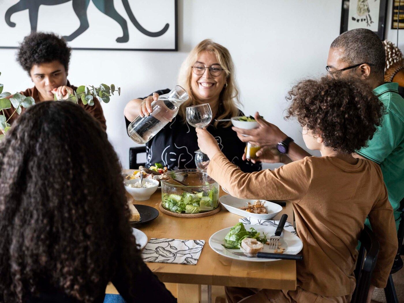 The family enjoy lunch at the dining room table. Cecilia is smiling.