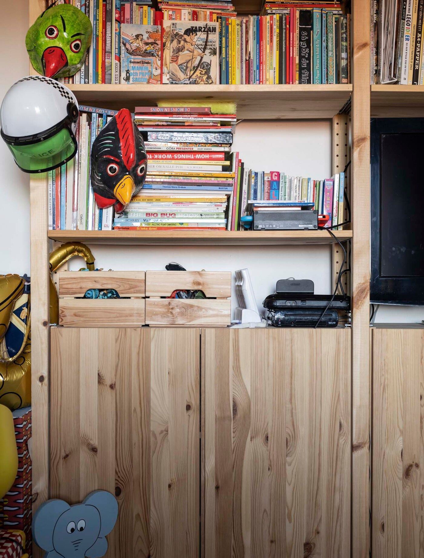A wooden IVAR storage unit filled with books in Victor's room