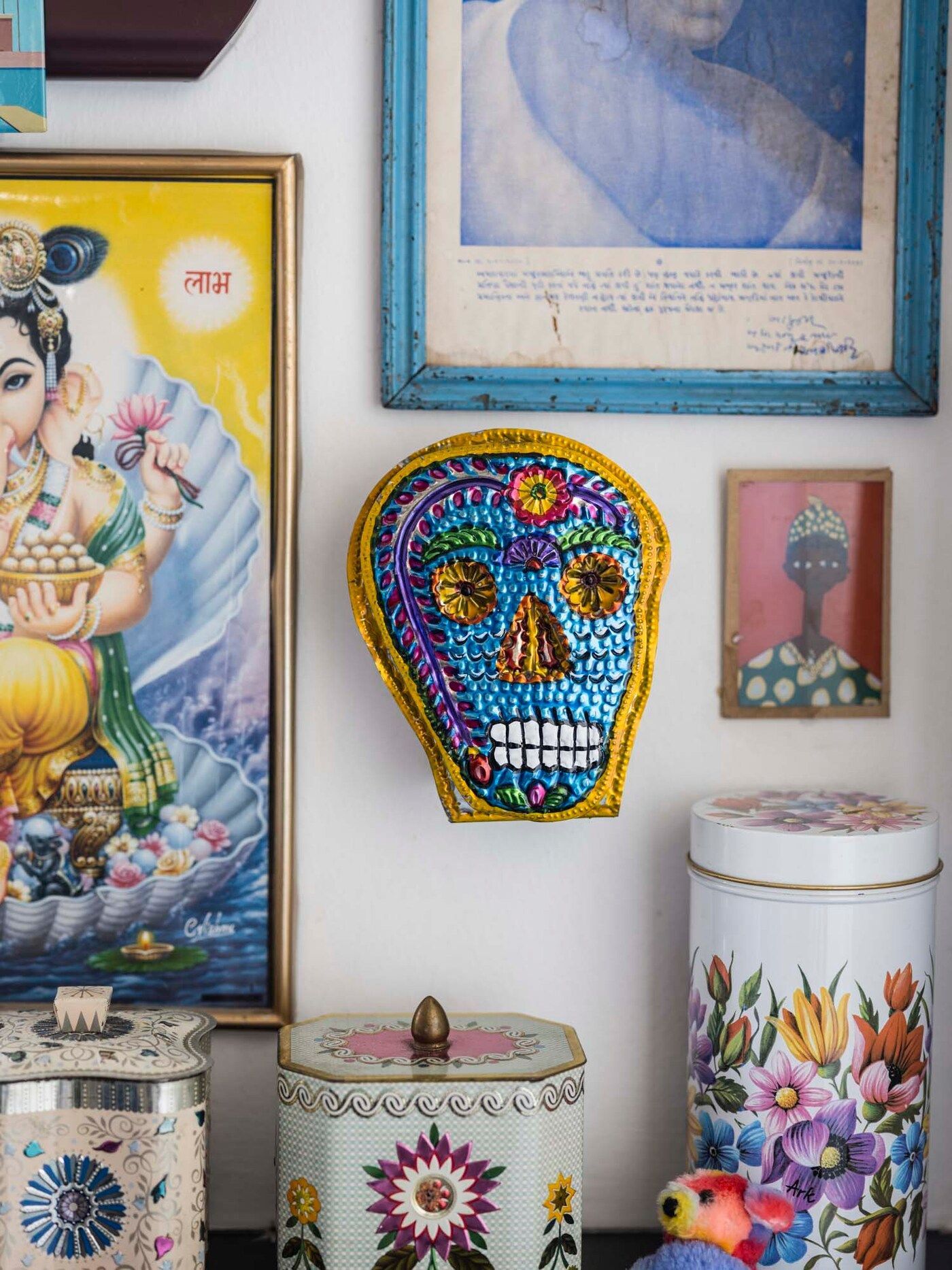 A Mexican style mask face hangs on the wall next to pictures and ornamental cannisters.