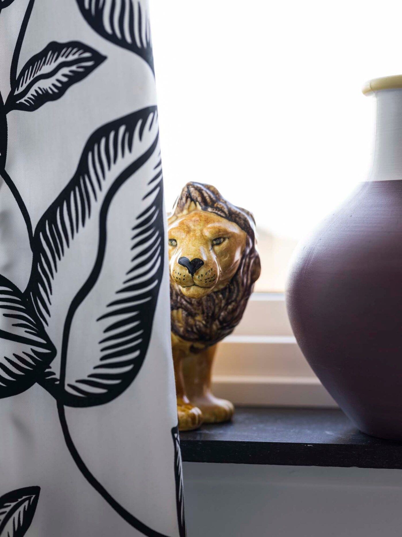 An ornamental lion peeps out from behind the black and white curtain.