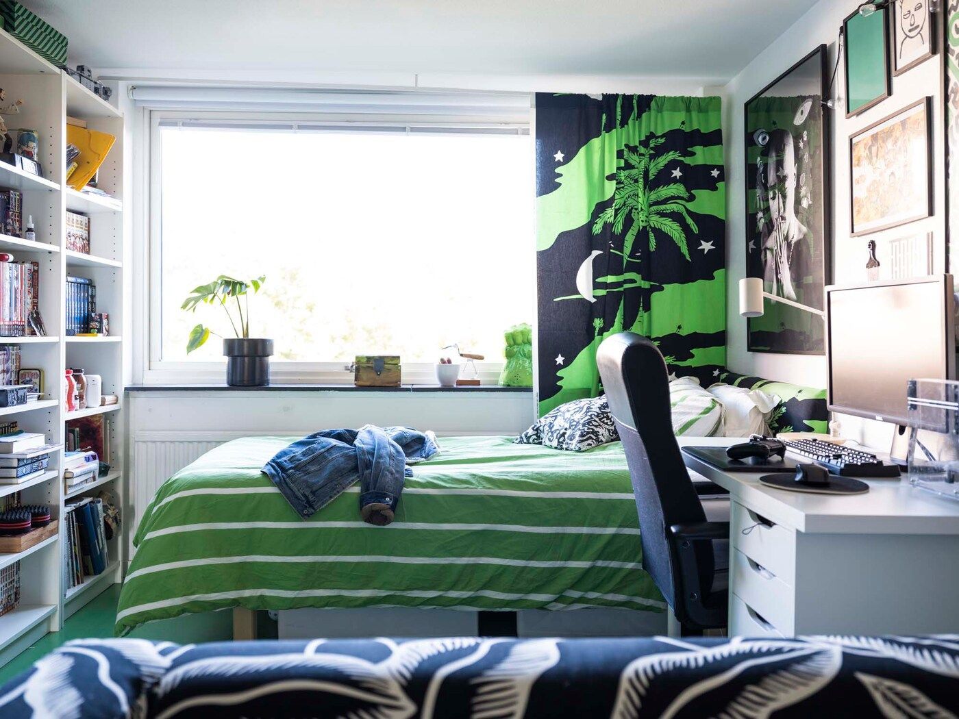 Maxime's bedroom has a sofa in the foreground, a workdesk with computer and a bed in the background.