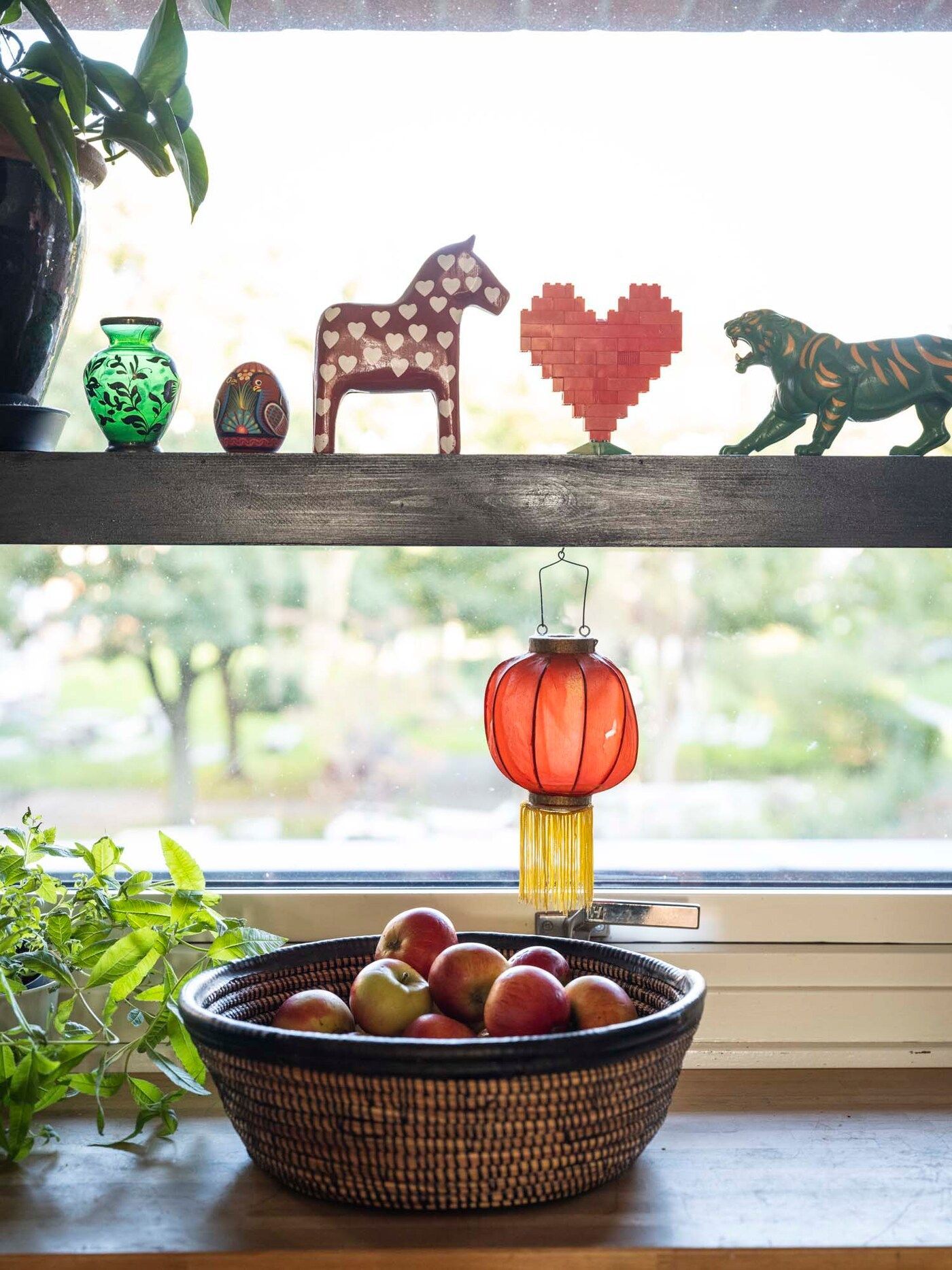 The kitchen windowsill features ornaments, a Chinese lantern and a bowl of apples.