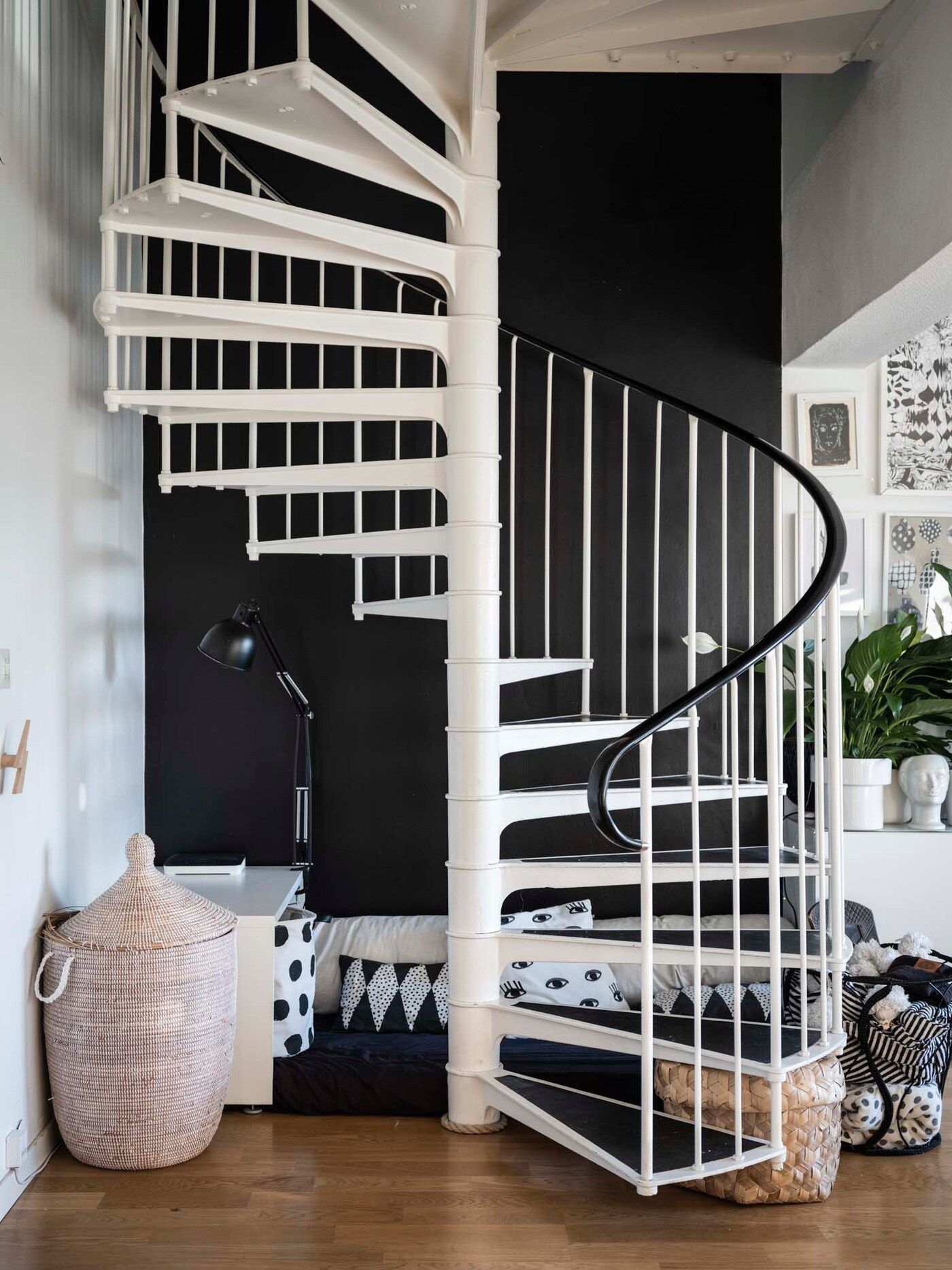 A spiral staircase with a rattan basket at the foot of the stairs.
