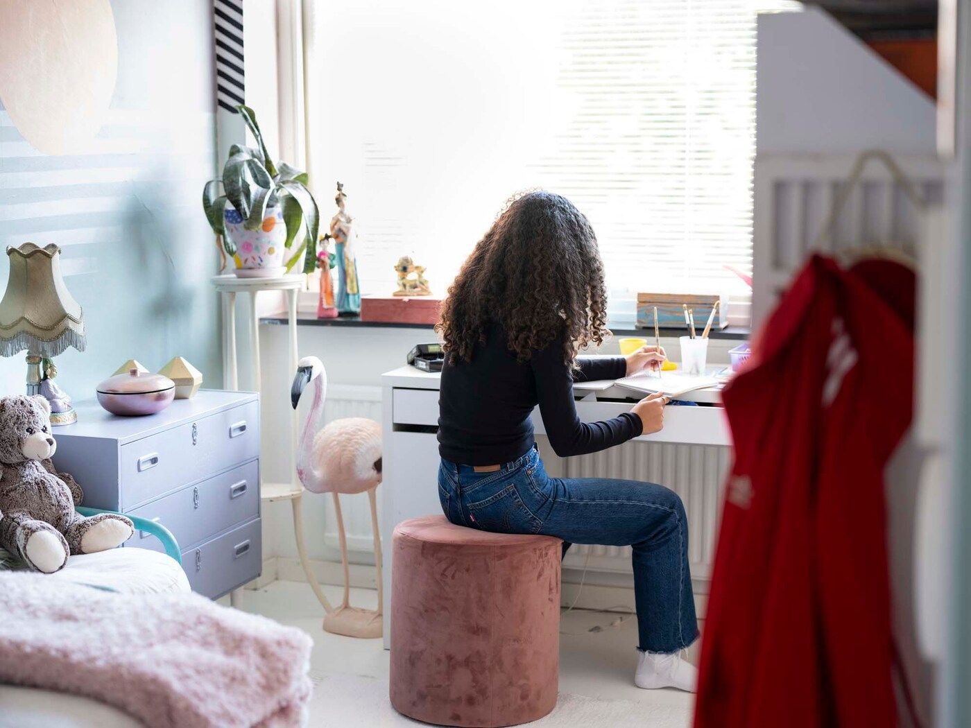 Anais in her bedroom. She is painting at her desk.