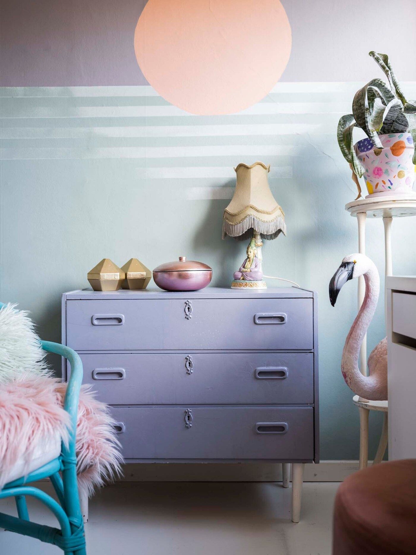 Anais' room. A lilac chest of drawers with a flamingo to the right and a chair to the left.