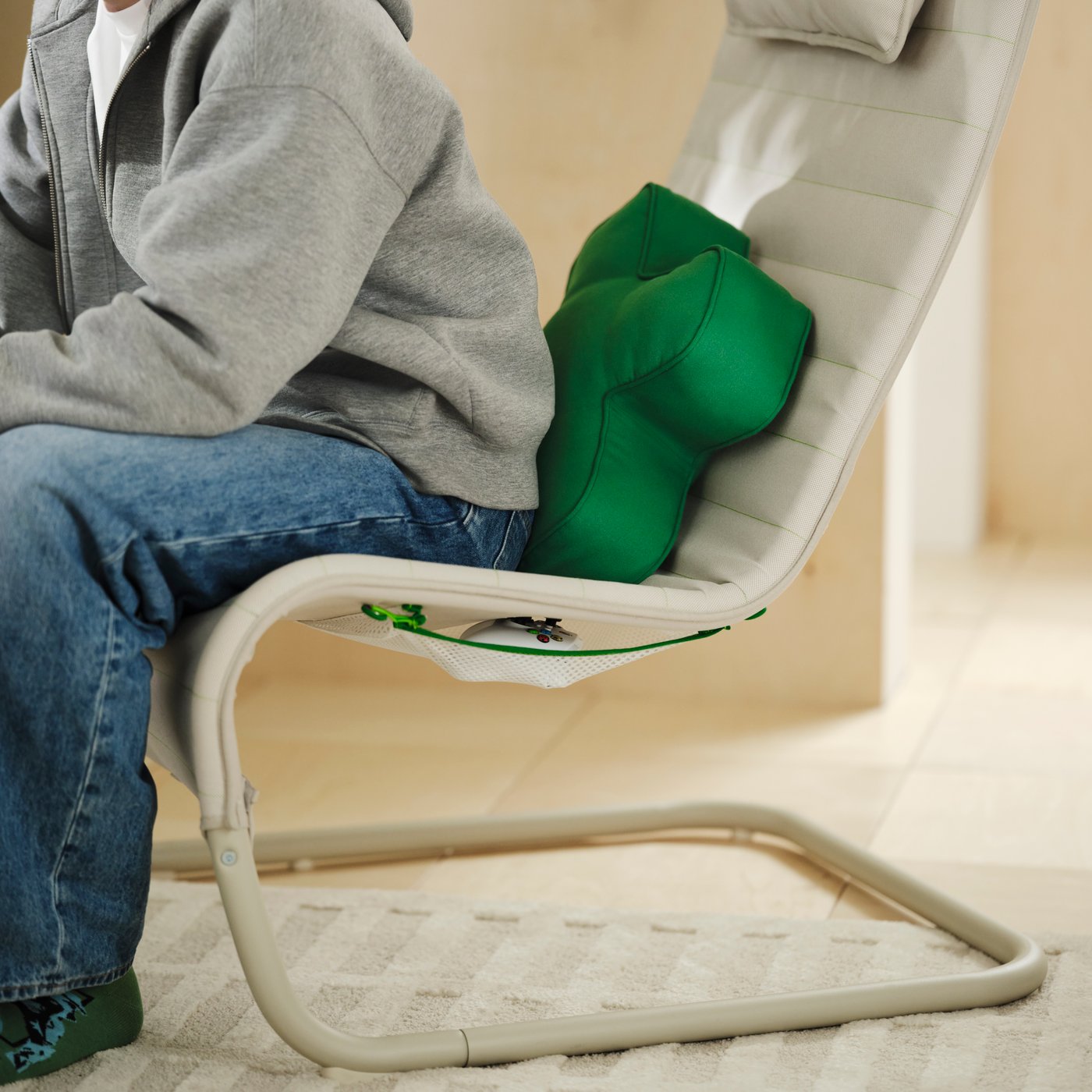 The YXSTABY gaming lounge chair with the YXSTABY cushion on a cream rug with a person in a grey hoodie and jeans sitting in the chair.