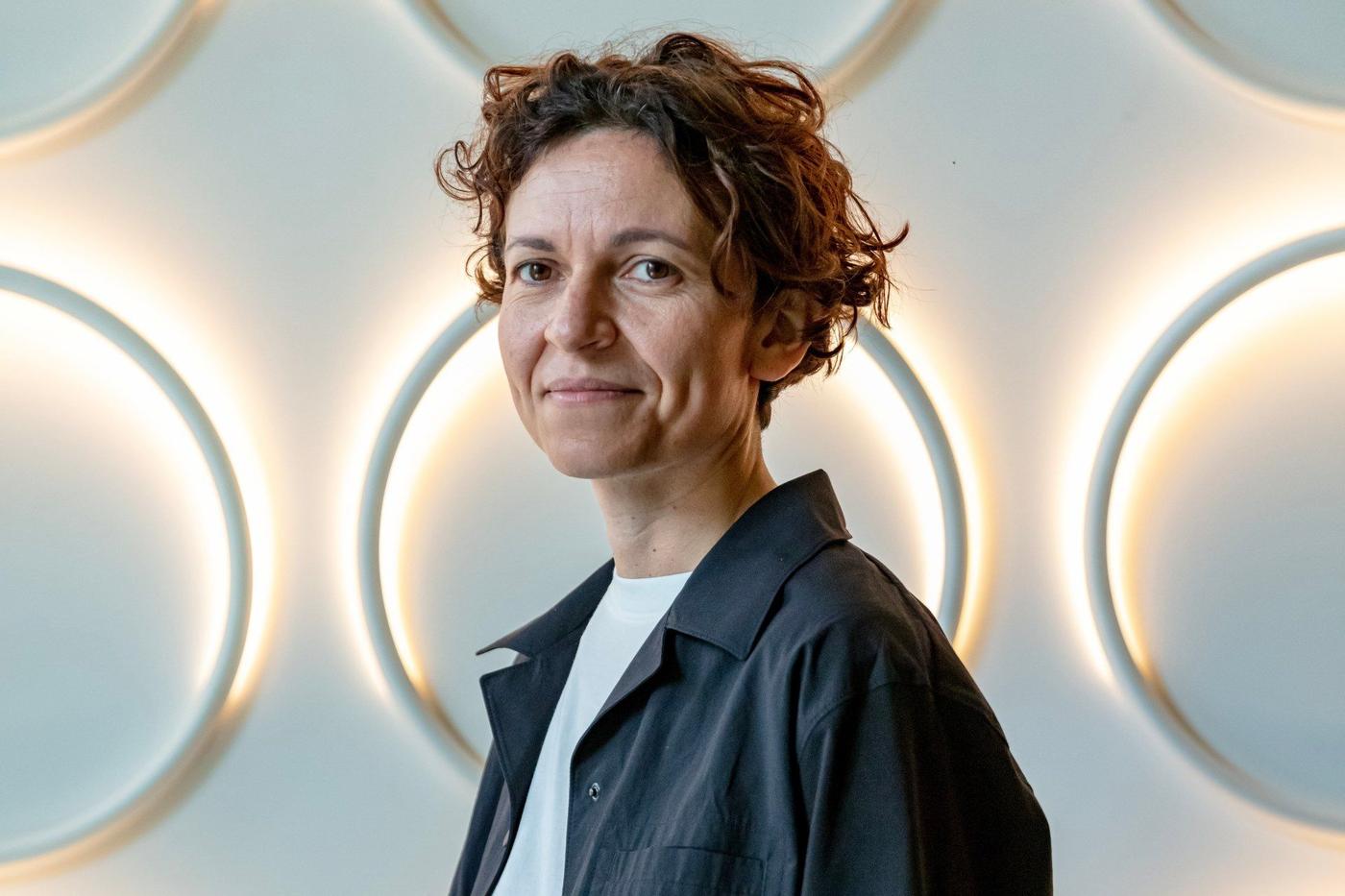 Chiara Ripalti stands in front of a wall illuminated with circular ring lights from the VARMBLIXT collection.