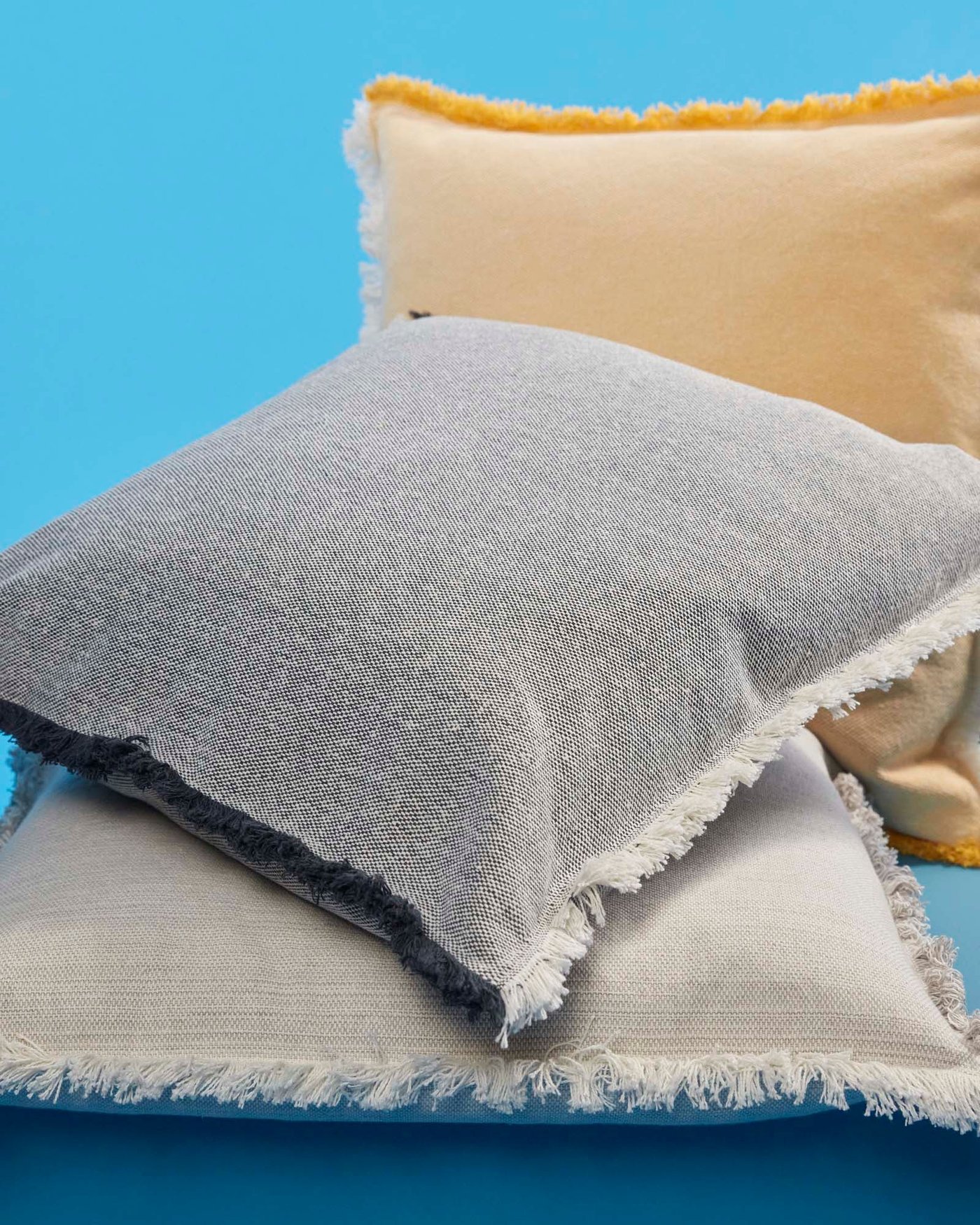 A pile of three VÄXELBRUK cushions on a bright blue background.