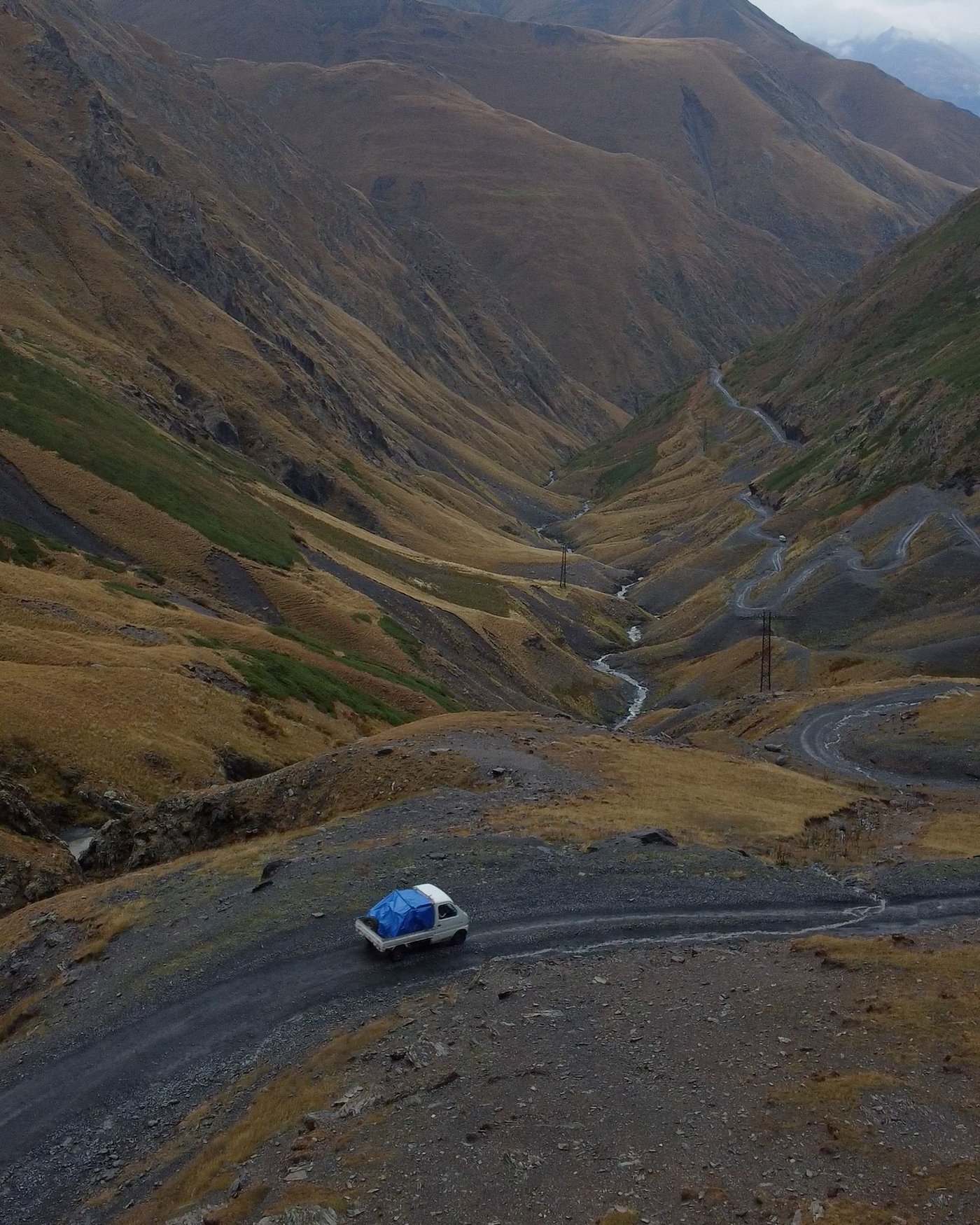 A white delivery van navigates a mountainous road in Georgia.