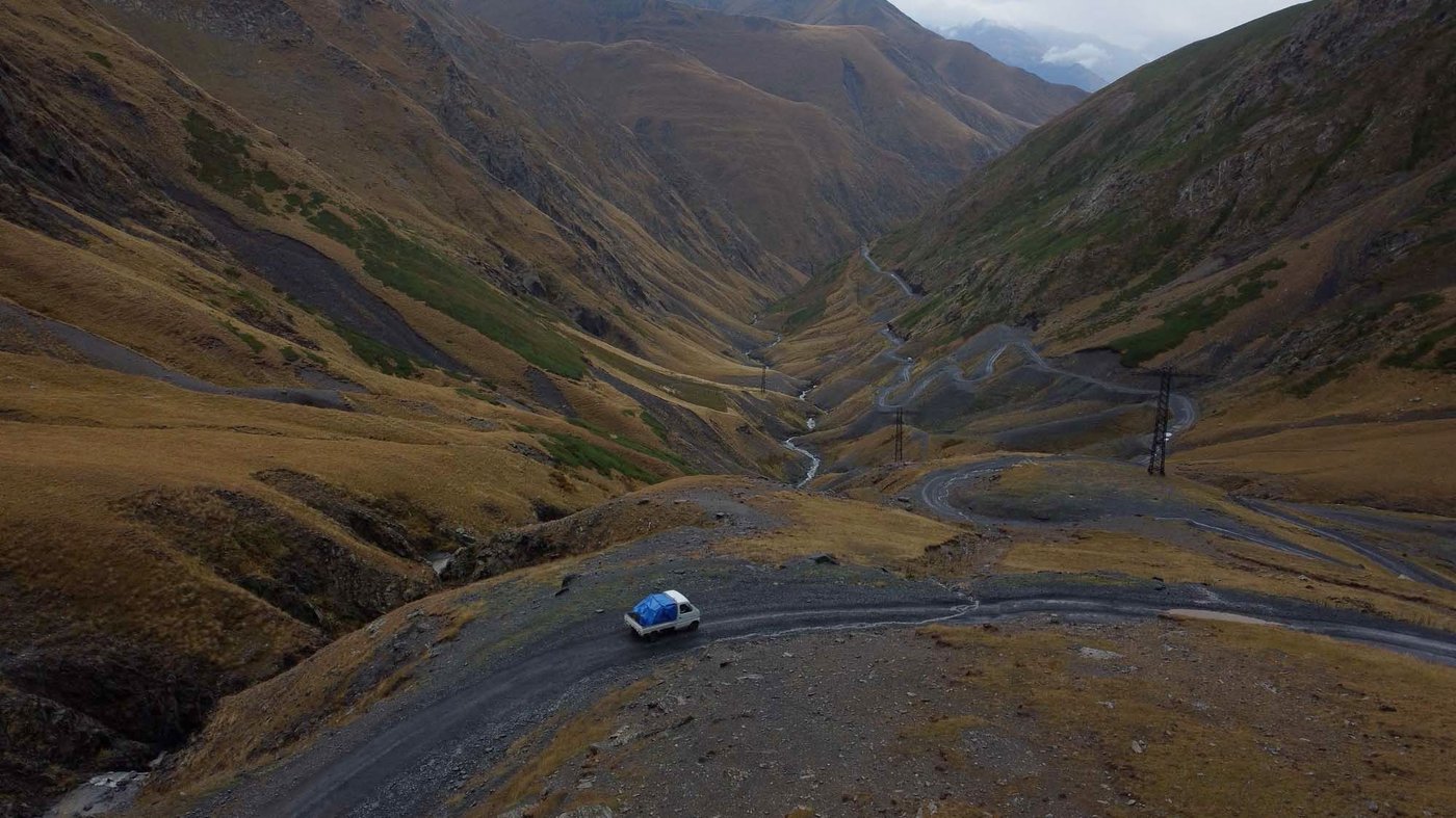 Panoramic view of a white delivery van navigating a mountainous road in Georgia.