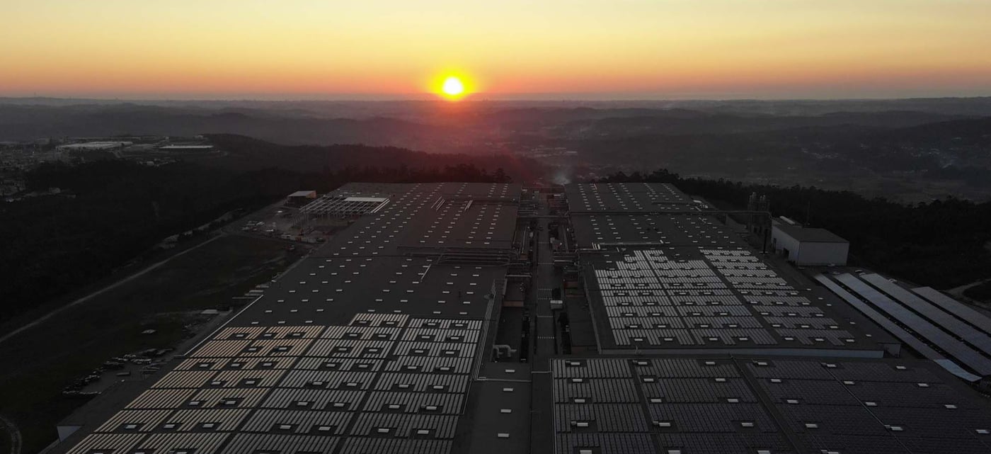 The sun rises over the countryside. In the foreground are rows and rows of solar panels, creating solar energy.
