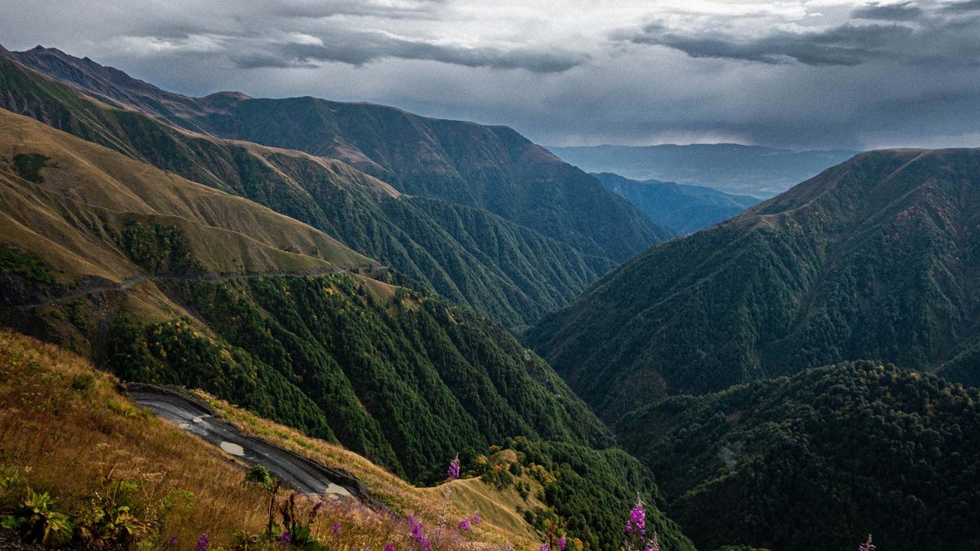 Scenic view of Georgian mountains in dramatic afternoon light with thick clouds.