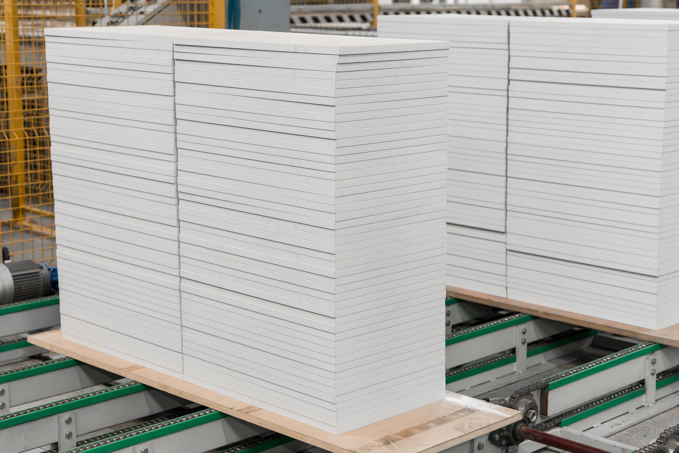 White kitchen fronts in two stacks on a production line conveyor belt in a factory setting.