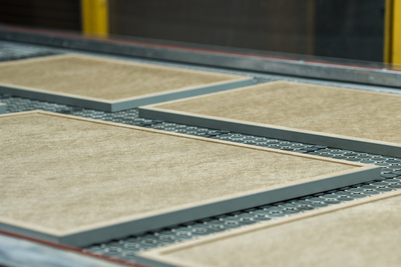A close-up of unfinished kitchen fronts on a conveyor belt.