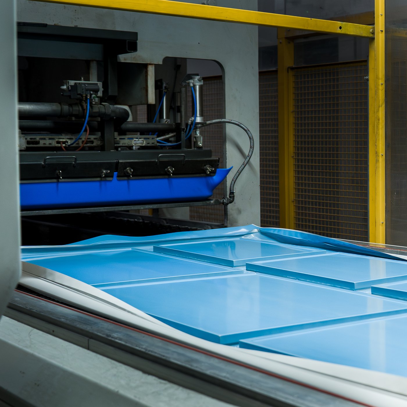 Kitchen fronts covered in a blue foil laminate on a conveyor belt.
